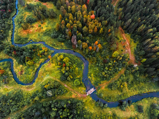 Aerial view of the small river with bridge and colorful autumn forest. Russia