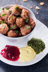 Meatballs in a cup with various sauces on a plate, grey colors