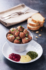 Meatballs in a cup with various sauces on a plate, grey colors