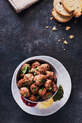 Meatballs in a cup with various sauces on a plate, grey colors