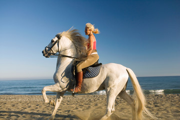 Woman riding horse on the beach