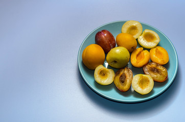 Summer fruits: apples, pears, apricots, plums on a blue plate