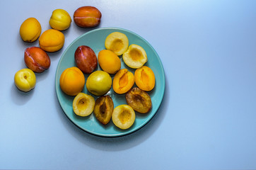 Summer fruits: apples, pears, apricots, plums on a blue plate