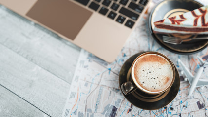 Coffee cups, notebooks, plane cakes and maps are placed on the table.