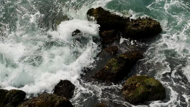 waves with foam of the sea in Montenegro beating on the rocks covered with moss and Tina
