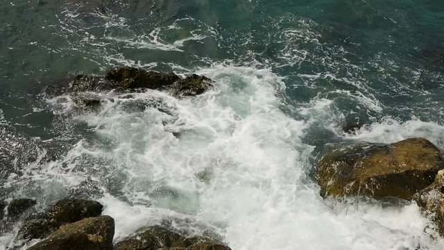 waves with foam of the sea in Montenegro beating on the rocks covered with moss and Tina