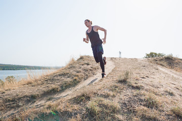 Naklejka na ściany i meble Running sport. Man runner sprinting outdoor in scenic nature. Fit muscular male athlete training trail running for marathon run.