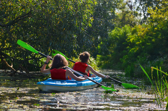 Family kayaking, mother and child paddling in kayak on river canoe tour, active autumn weekend and vacation, sport and fitness concept
