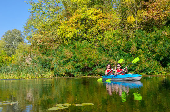 Family kayaking, mother and child paddling in kayak on river canoe tour, active autumn weekend and vacation, sport and fitness concept
