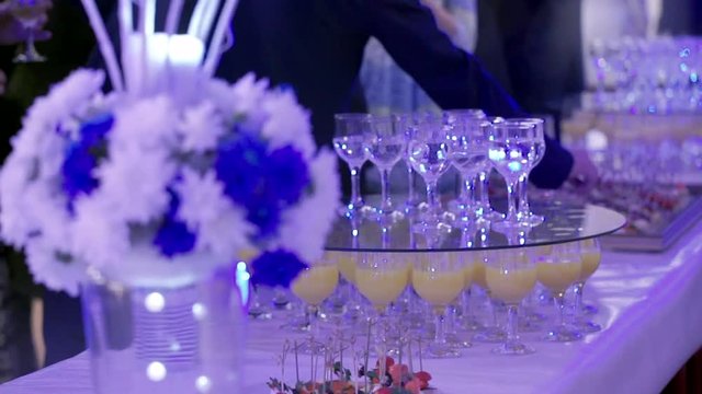 Guests are treated to snacks at a gala event. The table is decorated with flowers. The man takes a snack from the table.