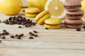 Yellow and brown french macarons with lemons and coffee beans on the wooden board
