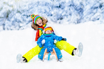 Fototapeta na wymiar Mother and baby on sleigh ride. Winter snow fun.