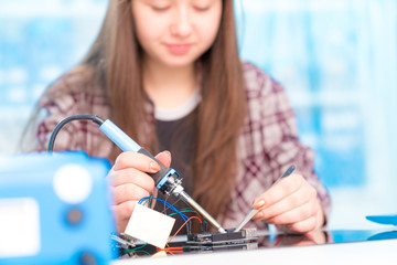 Schoolgirl in laboratory robots debug microcontroller