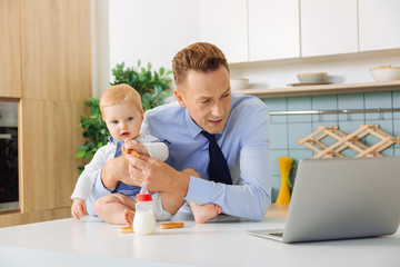 Pleasant adult man standing in front of the laptop