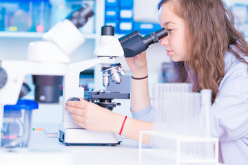 schoolgirl girl looks through a microscope at a biology class at a gymnasium