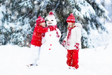 Kids building snowman. Children in snow. Winter fun.