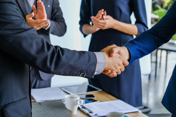 Business handshake at meeting or negotiation in the office, close-up. Partners are satisfied because signing contract