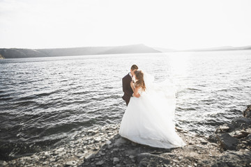 Wedding couple kissing and hugging on rocks near blue sea