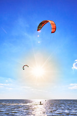 Man riding a kite surfing on the waves in the summer.
