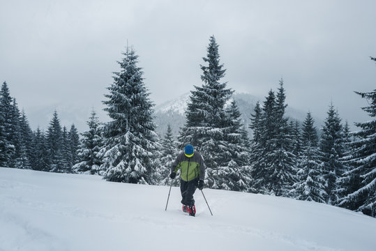 Adventurer, in snowshoes, climbs up the slope