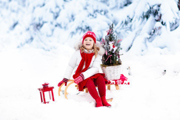 Fototapeta na wymiar Children with Christmas tree. Snow winter fun for kids.