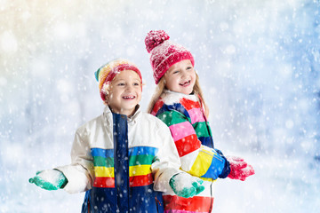 Kids playing in snow. Children play outdoors in winter snowfall.