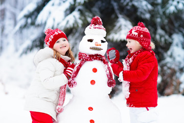 Kids building snowman. Children in snow. Winter fun.