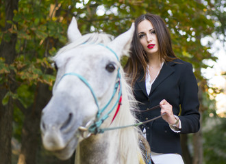 Young brunette beauty jokey girl riding horse in the park