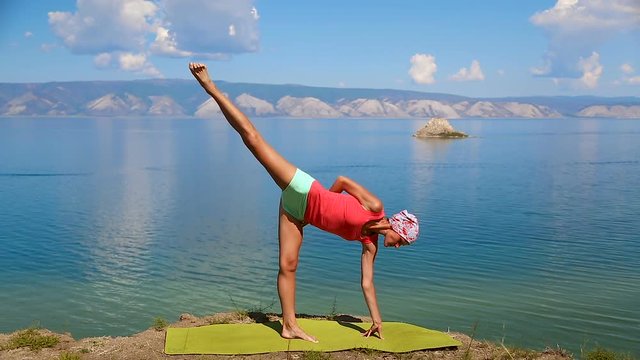 Slender fit woman doing yoga on exercise mat near blue lake. Olkhon Island, Baikal, Russia, Siberia. Healthy Active Lifestyle concept