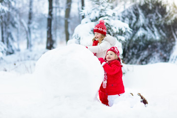 Fototapeta na wymiar Kids building snowman. Children in snow. Winter fun.