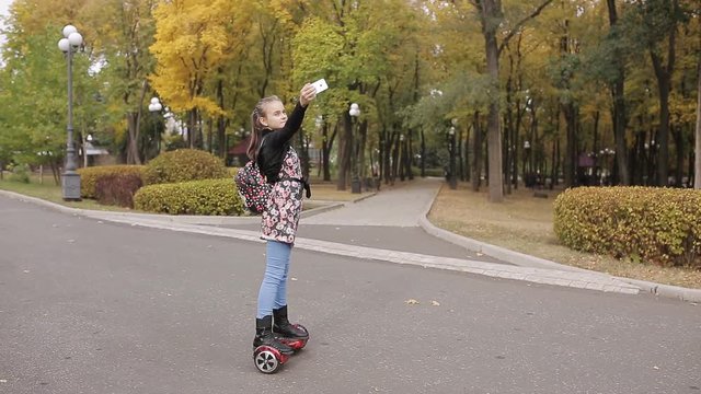 a teenage girl is riding an electronic scooter. the girl dances on gyroscope