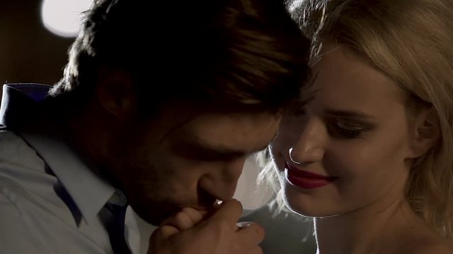 Handsome guy kissing hands of blond woman, young people in love, romantic mood