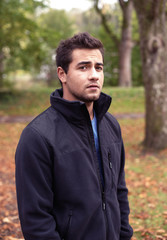 junger Mann im Park, teenager im Herbst mit dunkler Jacke