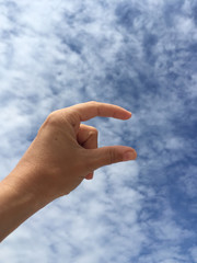 female hand holding virtual card or blank paper against blue sky