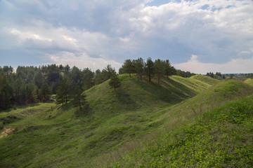 Fototapeta na wymiar Green grass on the brown iron ore ironstone hills slagheap