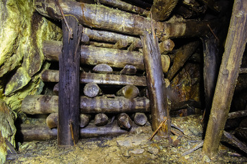 Underground abandoned ore mine shaft tunnel gallery passage with wooden timbering