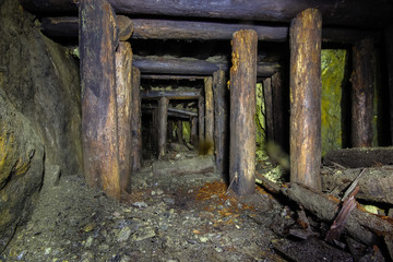 Underground abandoned ore mine shaft tunnel gallery passage with wooden timbering