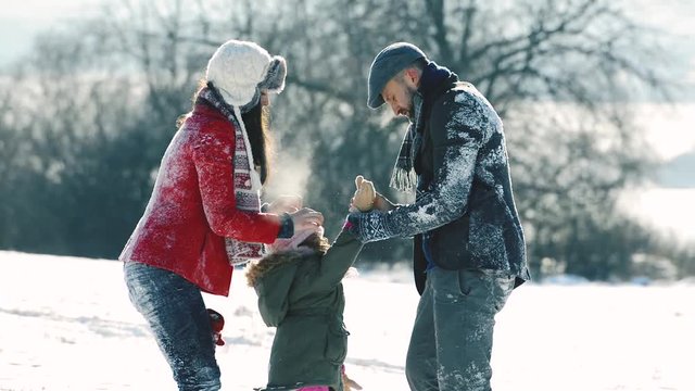 Father, mother and their daughter having fun in winter nature.
