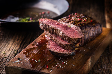Rindersteak. Saftige mittelgroße Rib-Eye-Steakscheiben auf Holzbrett mit Gabel- und Messerkräutern, Gewürzen und Salz