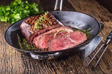 Beef steak. Juicy medium Rib Eye steak slices in pan on wooden board with fork and knife herbs...