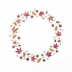 Round frame made of autumn leaves and pine cones on white background. Flat lay, top view, copy space.