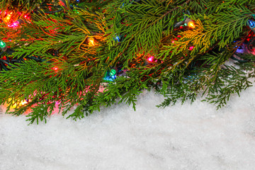 Christmas tree garland border with colorful string of lights with white snow copy space