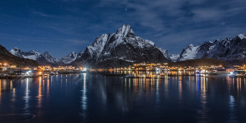 Village on the Lofoten Islands at night, in the foreground the sea in the background the mountains