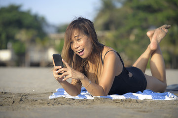 beautiful and happy Asian woman using mobile phone texting on internet social media smiling relaxed