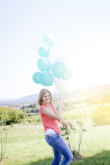 Happy Woman with balloons standing on the meadow