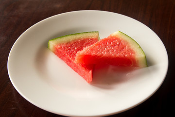 Slice of delicious watermelon on white plate background