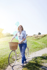 Happy Woman driving by bike with balloons