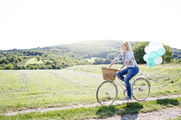 Happy Woman driving by bike with balloons