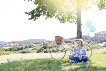 Happy Woman driving by bike with balloons