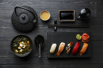 Nigiri Sushi set on wooden serving board and Miso soup on black wooden background